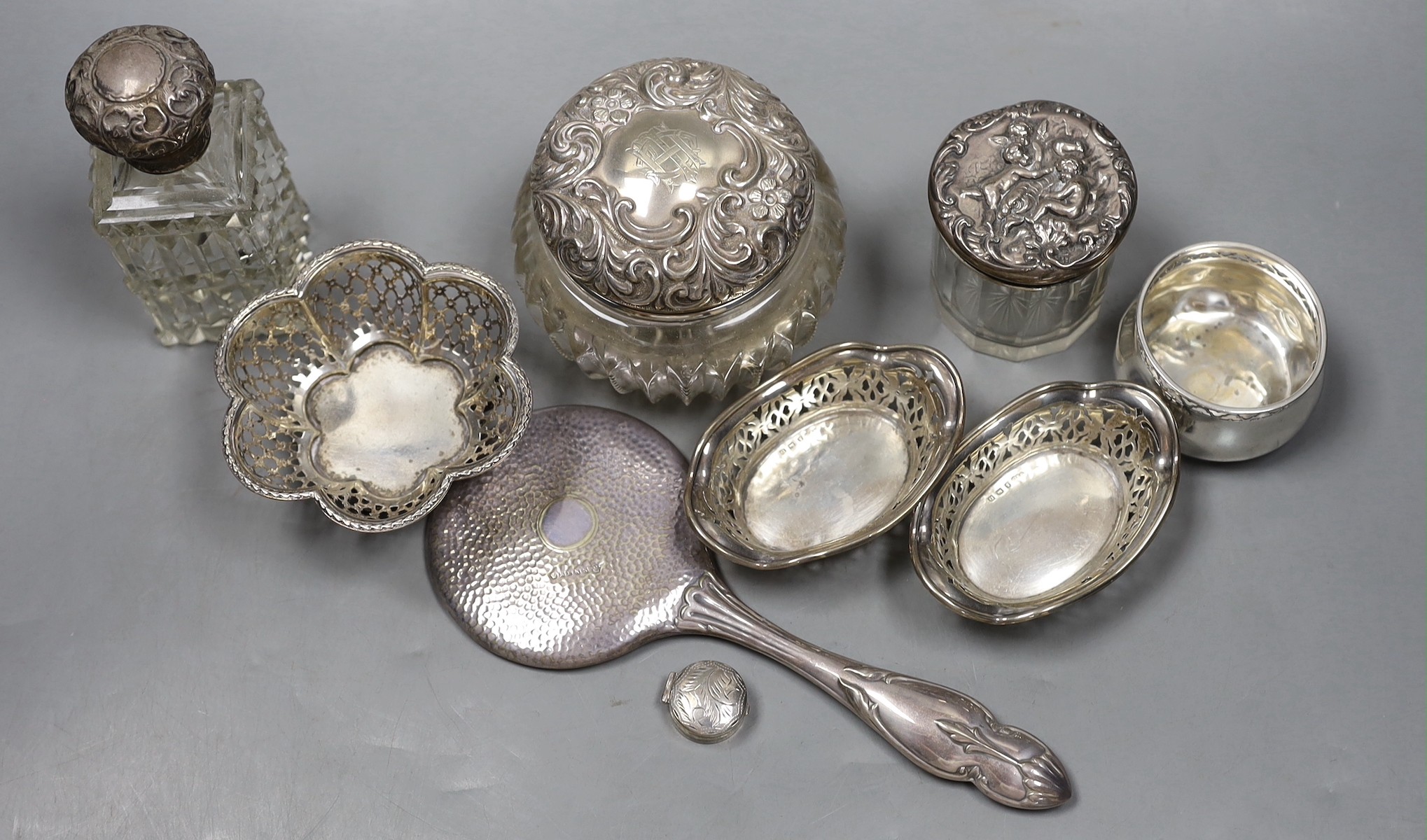 A small pair of George V pierced silver bonbon dishes, 92mm, two small pierced silver bowls, a modern silver pill box, three silver mounted glass toilet jars and a silver plated hand mirror.